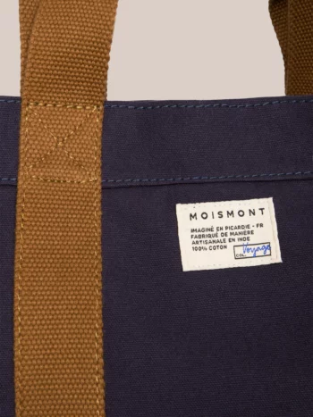 Detail van het Moismont-label, de handgeweven marineblauwe katoenstof en de okerbruine draagriemen